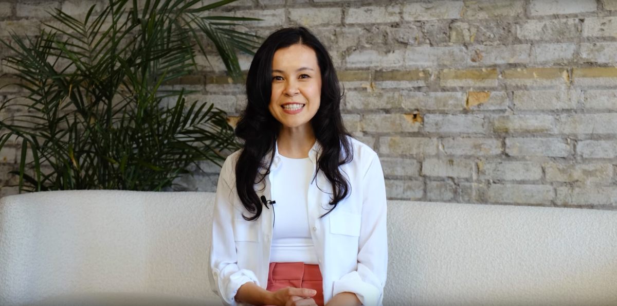 Screenshot of Kate Kamo McHugh, sitting on a white couch during a video interview.